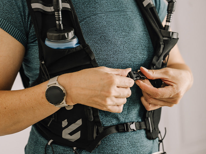 Person adjusting an Everpace vest with hydration flasks