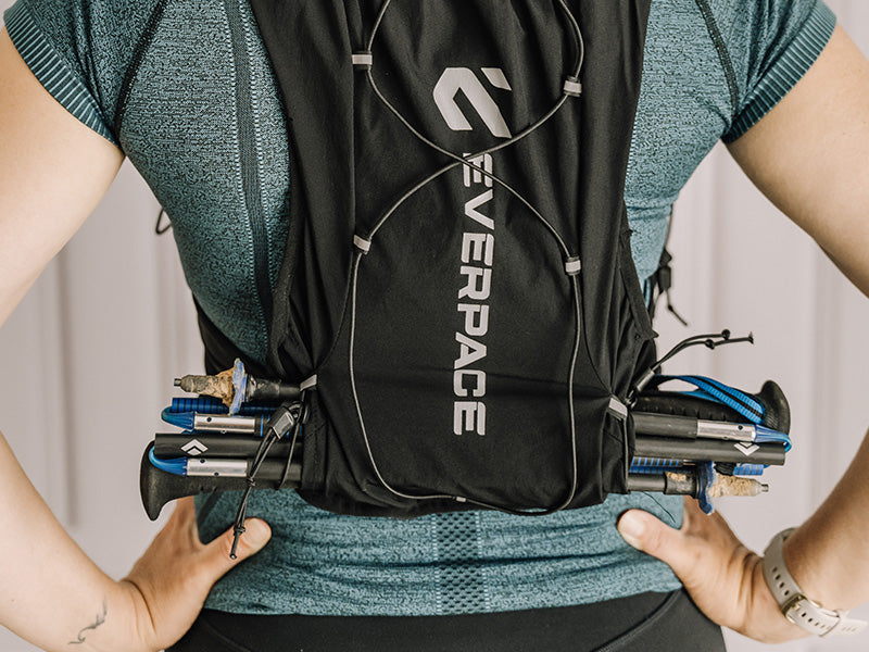 Person wearing a black Everpace vest with running poles attached
