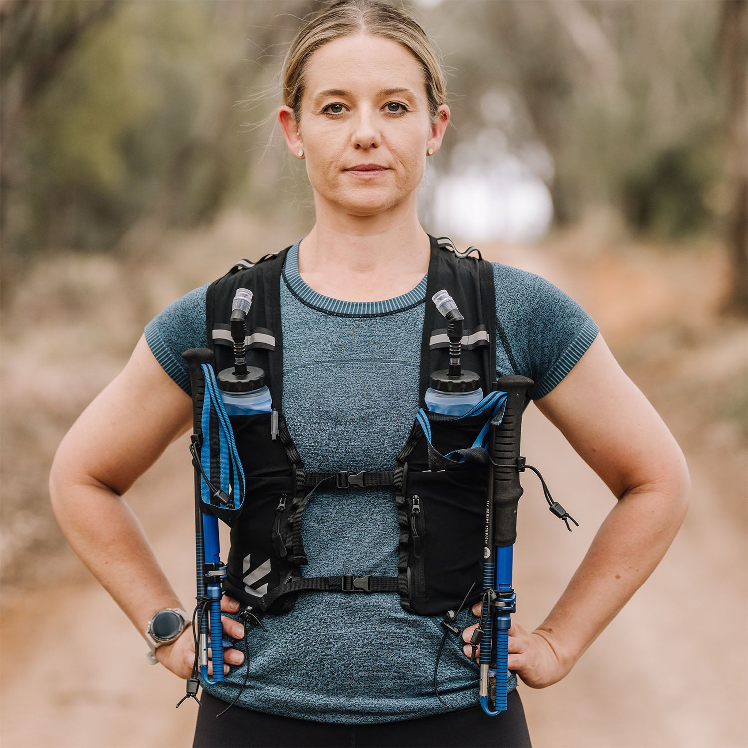 Woman wearing an Everpace hydration vest with water flasks on a blurred natural background