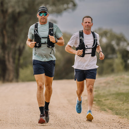 Two men running on a dirt tail, wearing Everpace hydration vests
