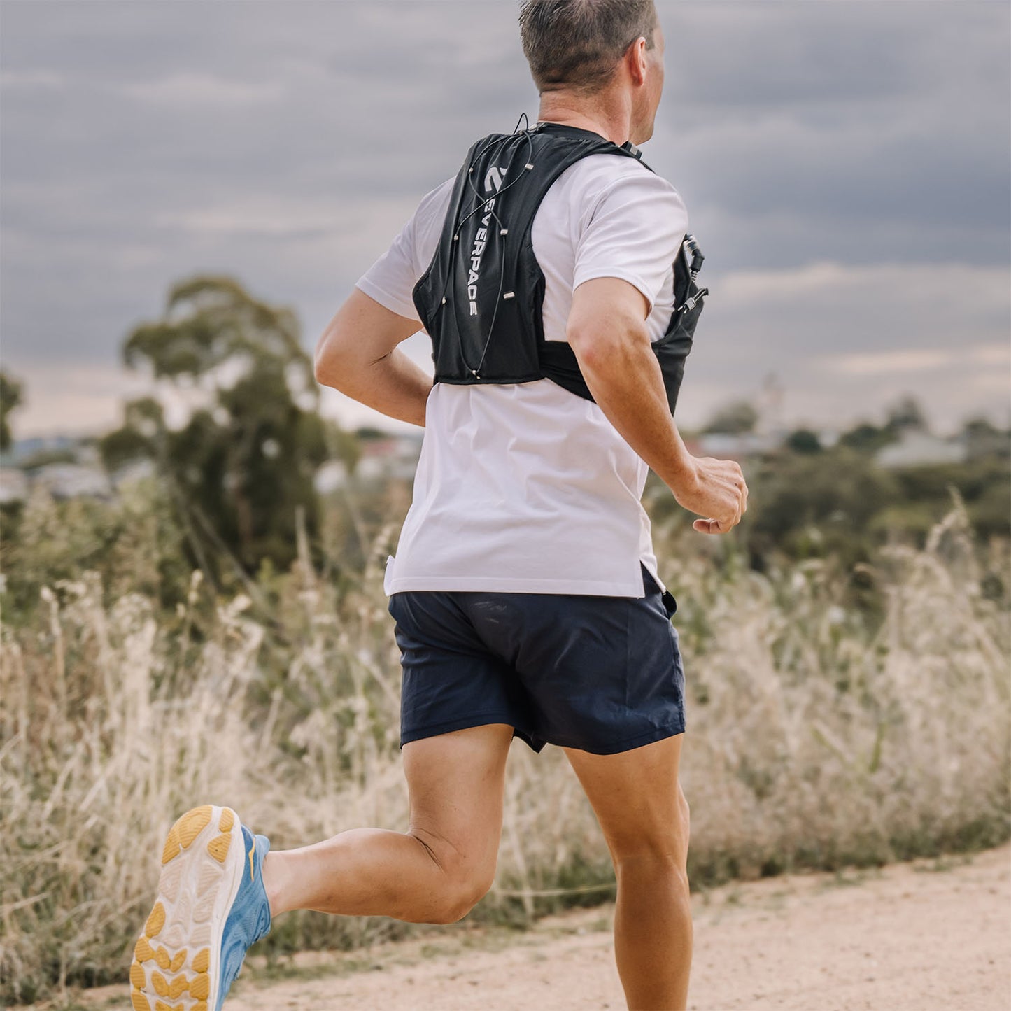Man running outdoors with an Everpace vest on a dirt trail