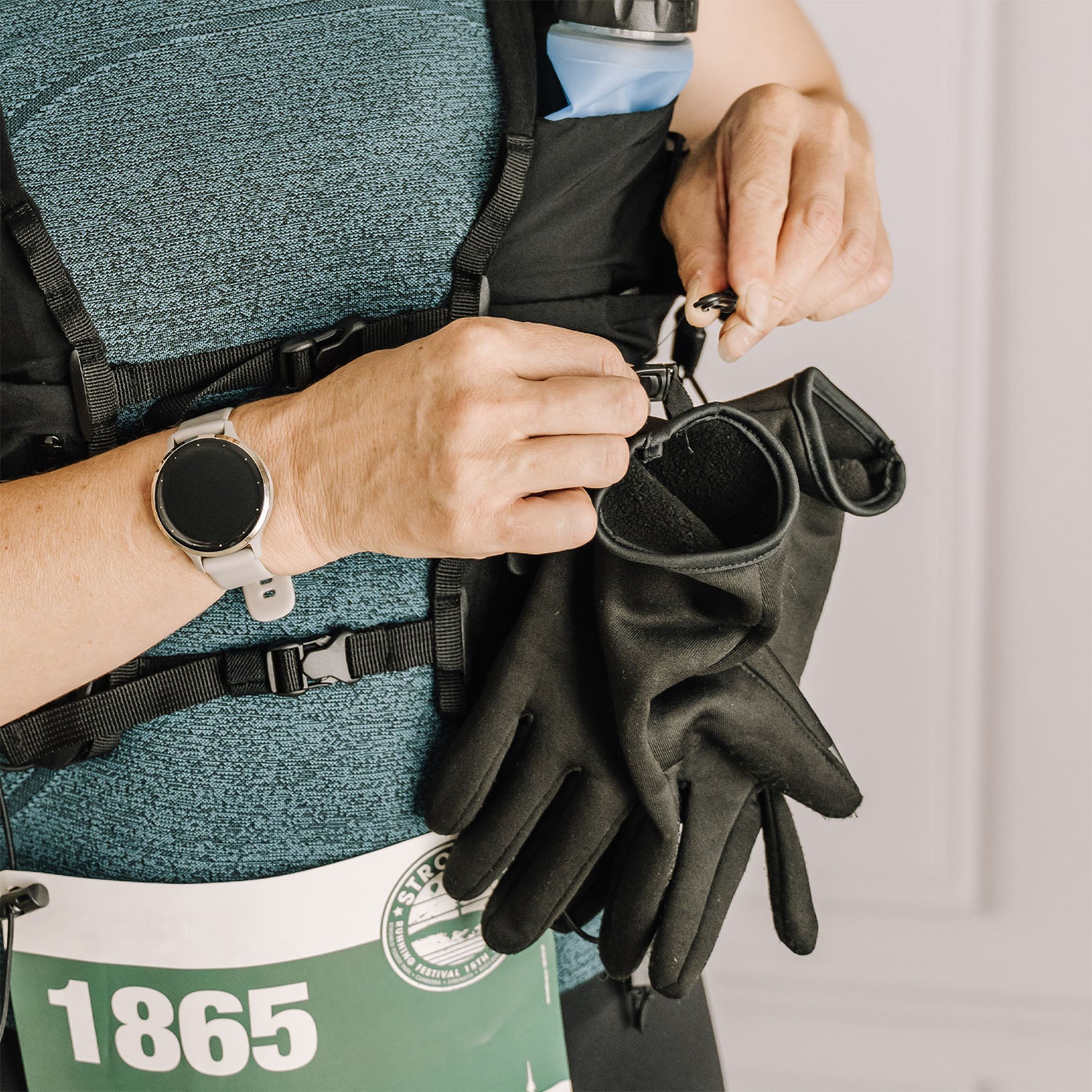 Person attaching black gloves to an Everpace running vest