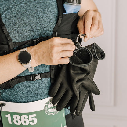 Person attaching black gloves to an Everpace running vest