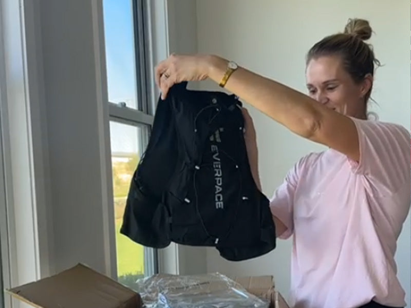 Person holding an Everpace vest as it is taken out of a shipping box